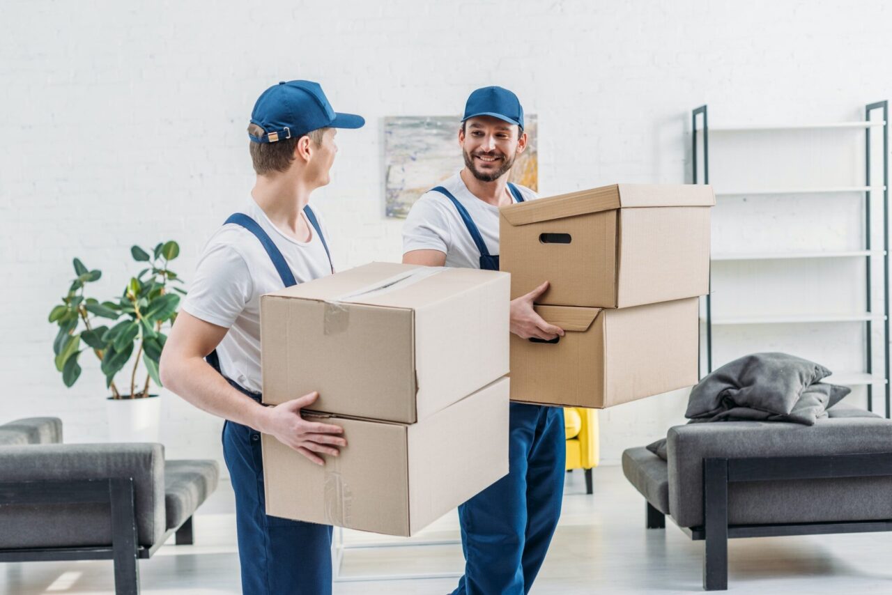 two movers in uniform carrying boxes